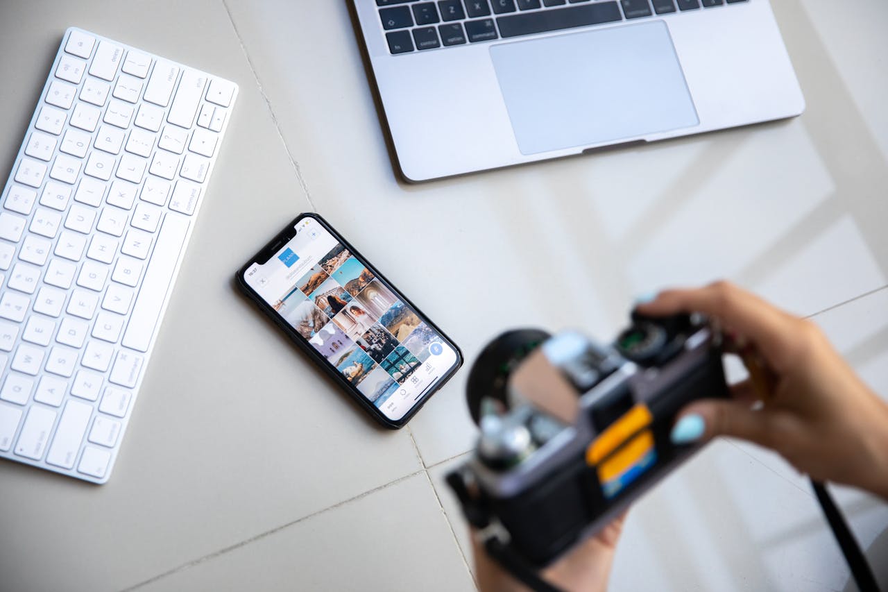 Contact Person using vintage camera with smartphone and laptop in creative setup.